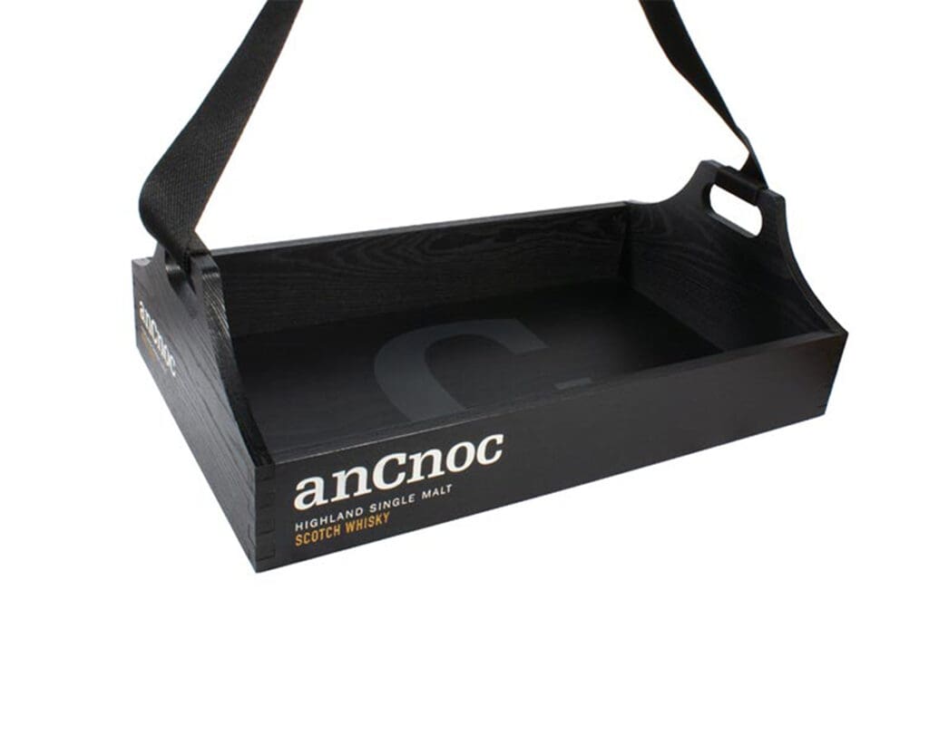 Black wooden anCnoc serving tray with webbing strap handle, printed branding and cut-out end handle