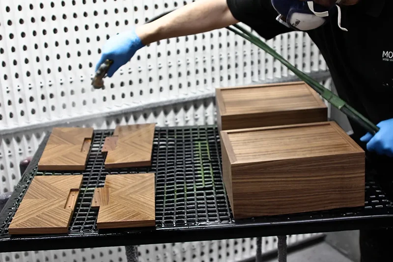 Morans Wood employee spray finishing a set of wooden boxes